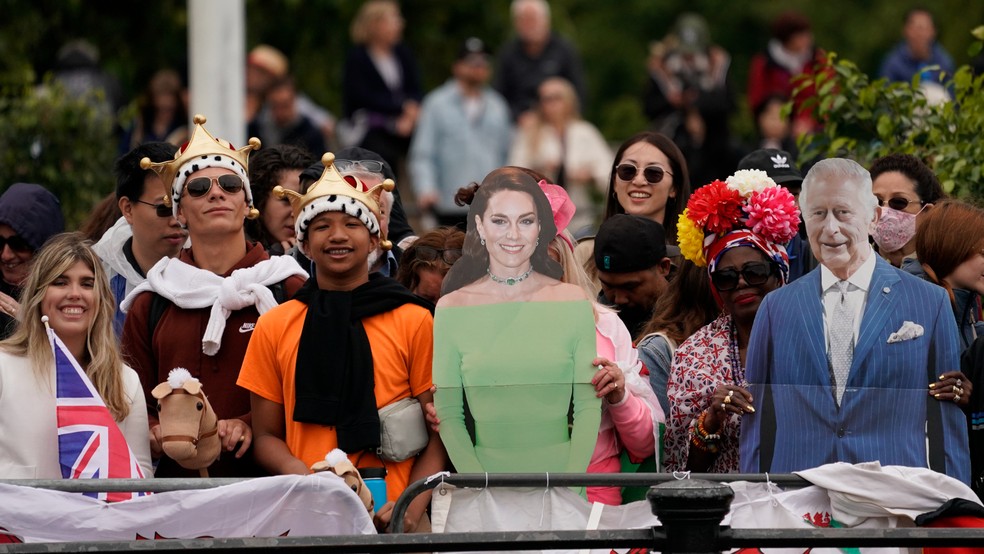 Fãs com totens de imagens de Charles III e Kate Middleton — Foto: Alberto Pezzali / AP Photo