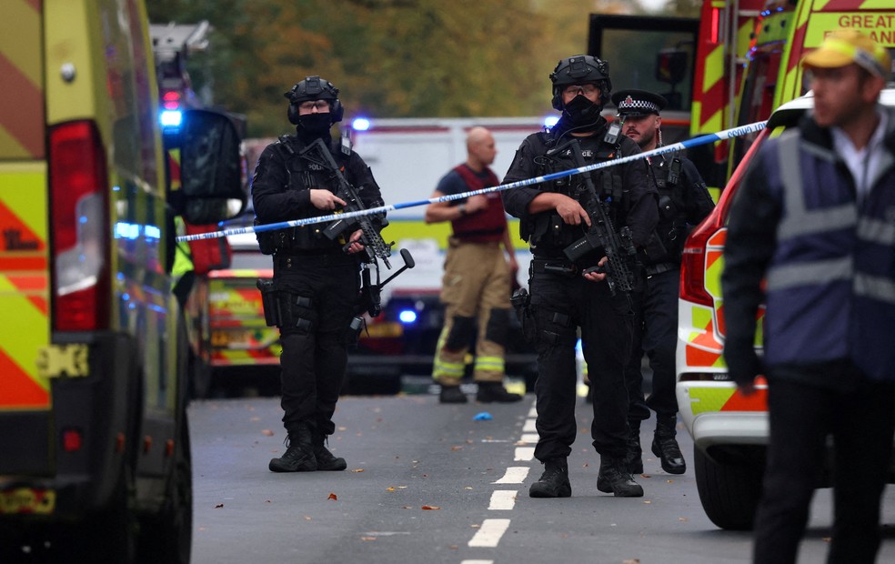 Agentes de roupa tática preta e fuzil cercam perímetro de atuação de equipes de emergência que responderam a ataque em frente à sinagoga em Manchester, no Reino Unido, em 2 de outubro de 2025. — Foto: REUTERS/Phil Noble
