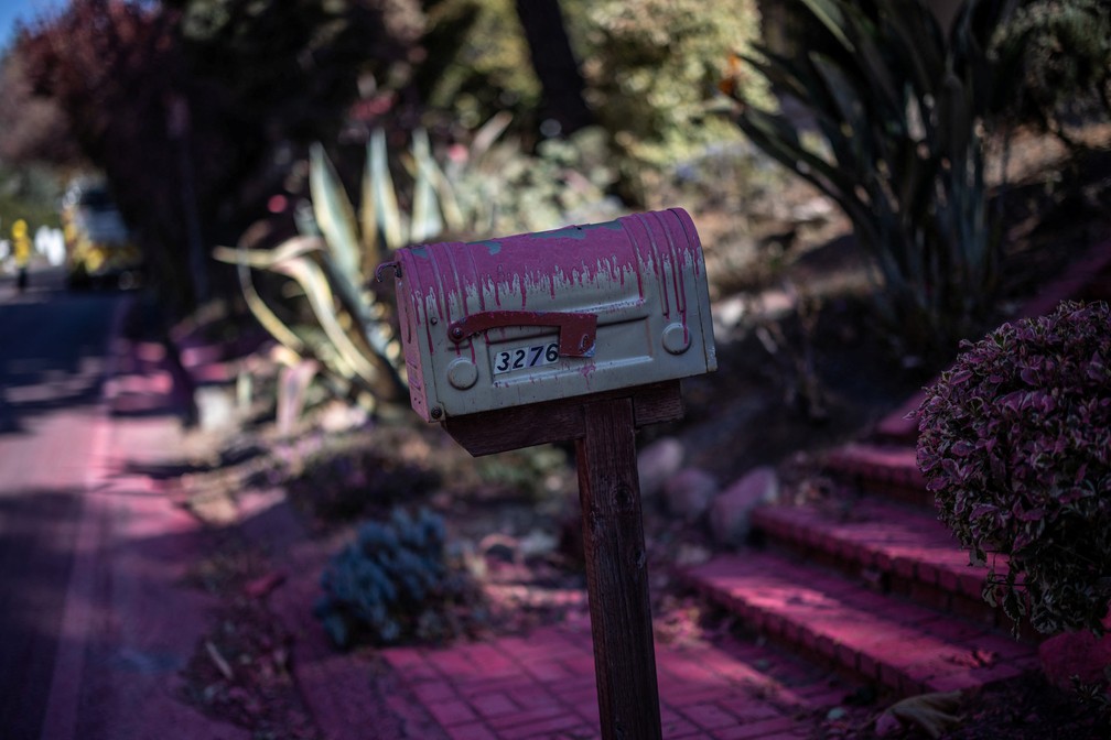 Uma caixa de correio coberta com retardante rosa de fogo é vista em Mandeville Canyon, bairro de Los Angeles atingido por incêndio — Foto: Carlos Barria/Reuters
