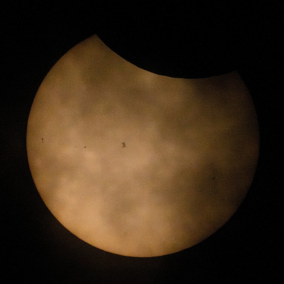 A Estação Espacial Internacional (ISS) aparece em silhueta ao passar diante do Sol durante o eclipse parcial, perto de Hodgdon, no estado do Maine, nos Estados Unidos, nesta quarta-feira (12). — Foto: Joel Kowsky/NASA via Reuters