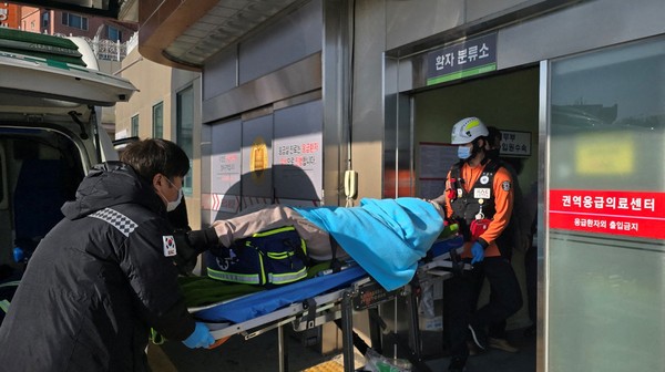 Vítima é resgatada por socorristas no Aeroporto de Muan, na Coreia do Sul, após avião explodir — Foto: Yonhap via REUTERS
