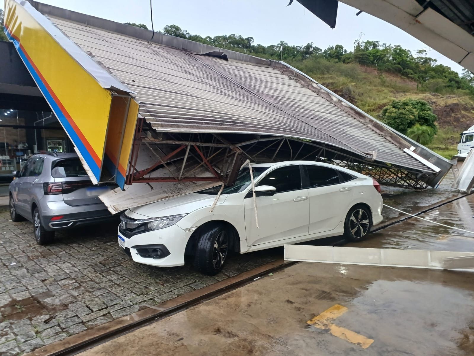 Telhado de posto parte ao meio e cai em cima de carro durante temporal em SC, e motorista sai ileso
