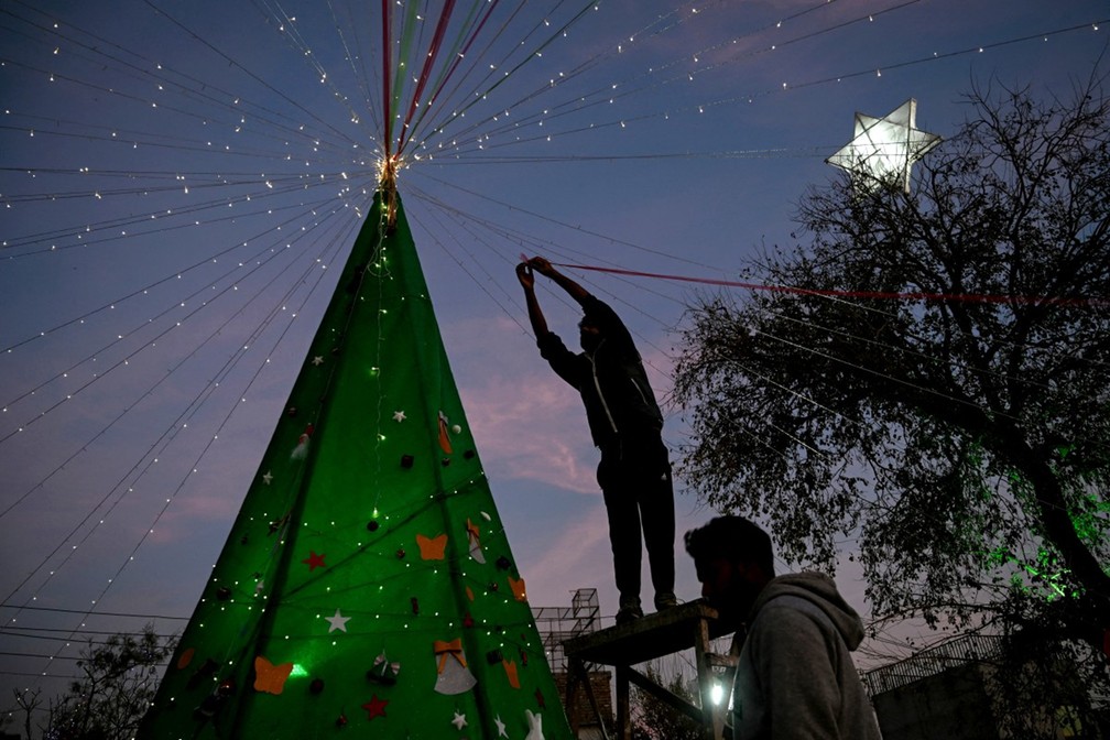 Homem decora árvore de Natal em Islamadab, no Paquistão — Foto: Farooq NAEEM/AFP
