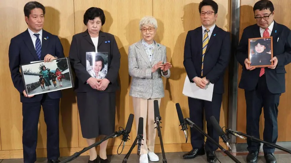 Soga (a segunda da esquerda para a direita) segurando uma foto de sua mãe faz campanha por outras pessoas sequestradas — Foto: BBC