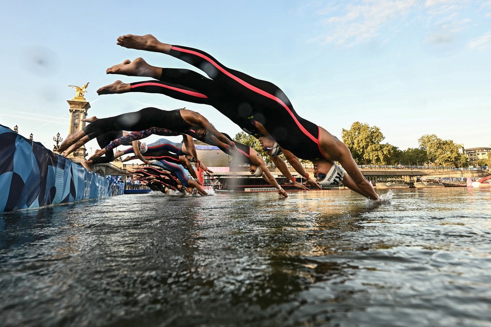 Atletas mergulham no Rio Sena, de Paris, para disputar a maratona aquática feminina. O nível de poluição das águas do rio foi motivo de debate antes e durante os jogos — Foto: Martin Bureau/pool via AFP