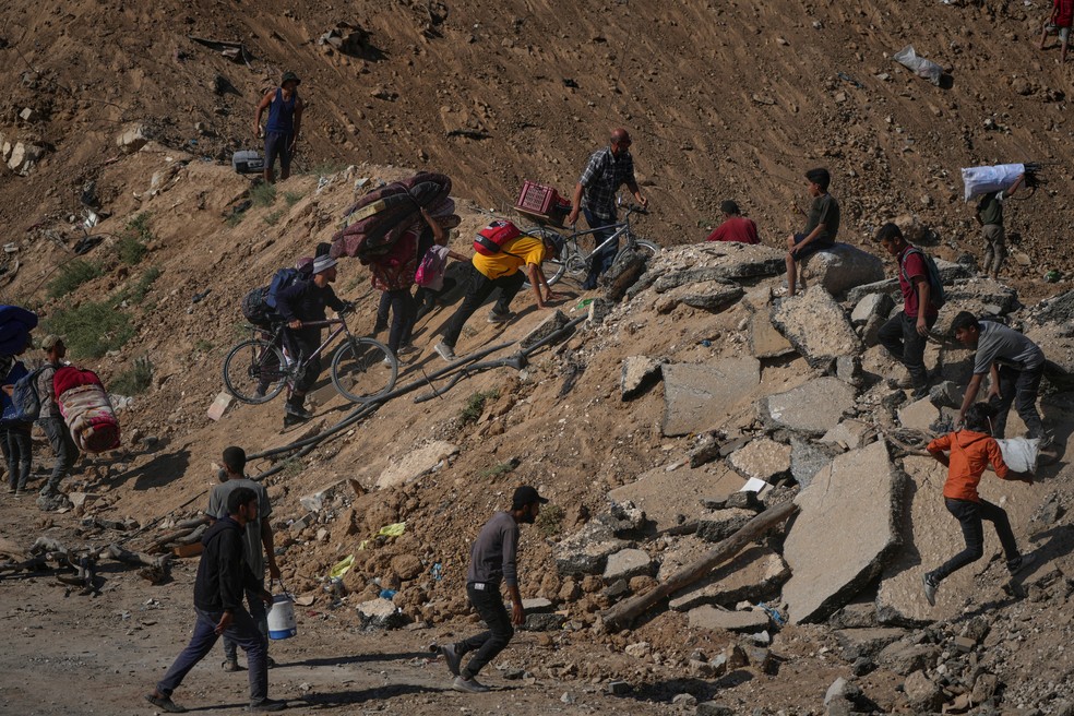 Palestinos deslocados seguem a pé do centro de Gaza em direção ao norte da Faixa de Gaza, sexta-feira, 10 de outubro de 2025 — Foto: AP Photo/Jehad Alshrafi