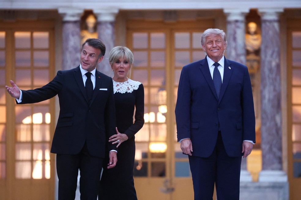 Emmanuel e Brigitte Macron recebem Donald Trump em frente ao Palácio de Versalhes, em 17 de junho de 2026 — Foto: Gonzalo Fuentes/Reuters