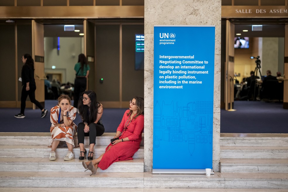 Delegados descansam do lado de fora do salão da assembleia no início de 15 de agosto de 2025, em Genebra, após as negociações para firmar um tratado histórico para combater o flagelo da poluição plástica terem terminado sem consenso — Foto: Fabrice COFFRINI / AFP