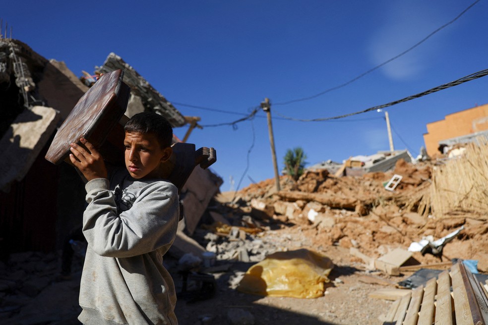 Jovem carrega móvel no dia 11 de setembro de 2023 em vilarejo nos arredores de Talat N'Yaaqoub, no Marrocos, destruído por terremoto — Foto: Hannah McKay/Reuters