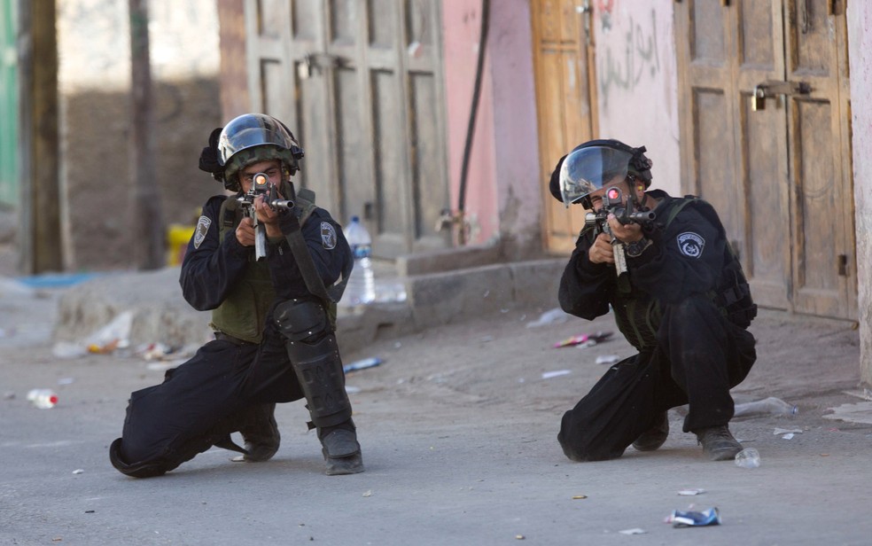 Em imagem de 2016, integrantes do Exército israelense apontam suas armas durante confronto com palestinos no campo de refugiados al-Fawwar, na Cisjordânia.  — Foto: Majdi Mohammed/AP