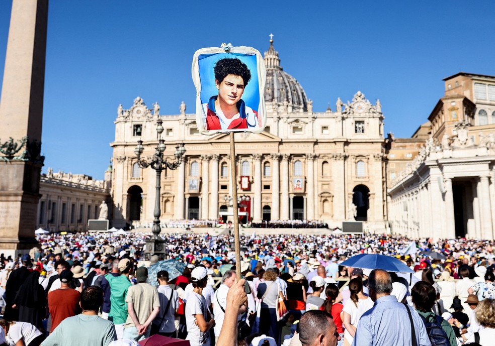 Pessoa segura uma obra de arte com o rosto de Carlo Acutis no dia em que o papa Leão XIV celebra uma missa solene pela canonização do jovem — Foto: Matteo Minnella/Reuters