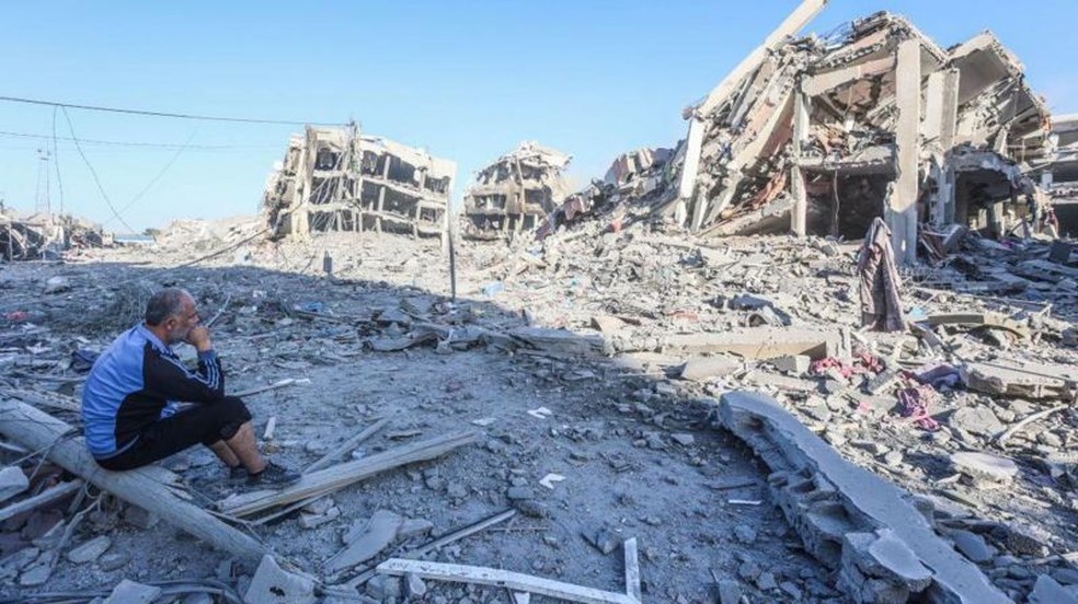 Desolado, um homem palestino observa a destruição de torres do bairro após os ataques de Israel — Foto: GETTY IMAGES