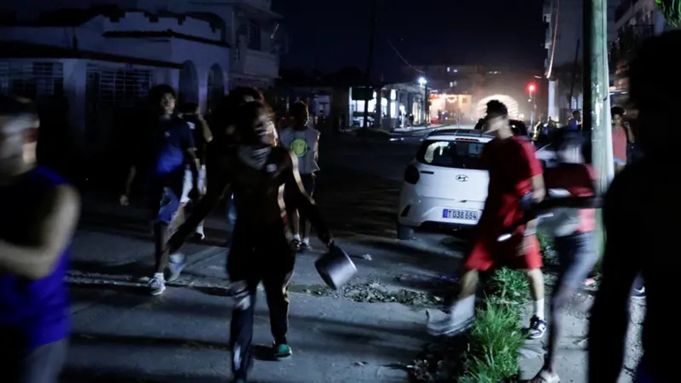 Manifestantes carregando pa.nelas e frigideiras correndo pelas ruas de Havanaund — Foto: Reuters via BBC