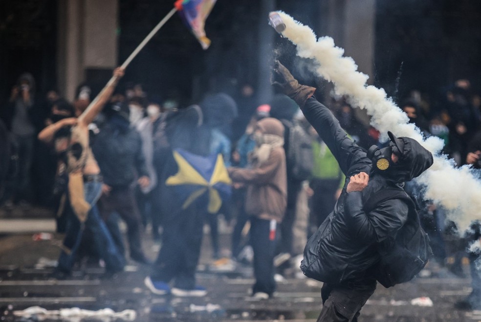 Um homem lança gás lacrimogêneo durante uma manifestação que exige que o governo do presidente argentino Javier Milei cumpra uma lei que atualiza o financiamento das universidades públicas — Foto: Emiliano Lasalvia/AFP
