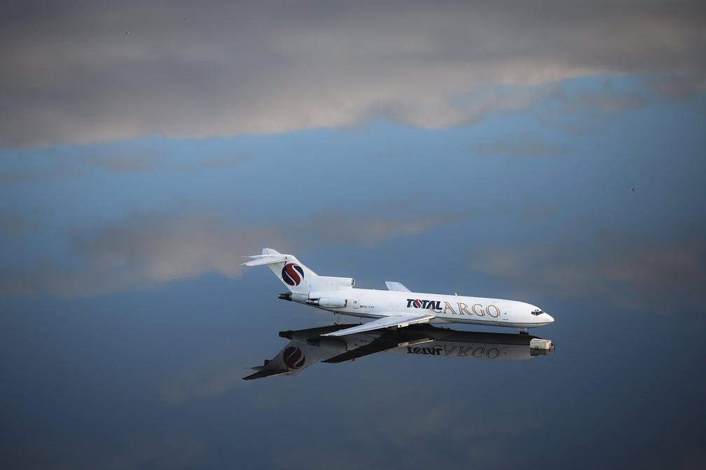 Um Boeing 727-200 é visto cercado pelas águas da enchente que refletem o céu no Aeroporto Internacional Salgado Filho, em Porto Alegre, RS. Fotografia feita durante a cobertura das enchentes que causaram sérios danos e mortes no estado foi vencedora na categoria individual na América do Sul — Foto: Anselmo Cunha/AFP via World Press Photo/Divulgação