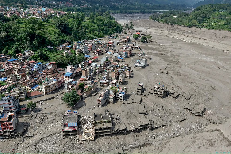 Casas ficaram parcialmente submersas em água barrenta às margens de um rio após enchentes repentinas em Trishuli Bazar, no distrito de Nuwakot, Nepal, em 26 de agosto de 2026. Uma grande enchente atingiu o distrito de Rasuwa, no norte do Nepal, em 26 de agosto, danificando estradas e infraestrutura de energia, enquanto as autoridades se esforçavam para avaliar a extensão da destruição. — Foto: PRABIN RANABHAT/AFP
