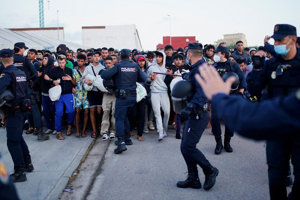 Polícia controlando transferência de imigrantes que estavam dormindo nas ruas de Ceuta para alojamento temporário — Foto: REUTERS/Ana Beltran