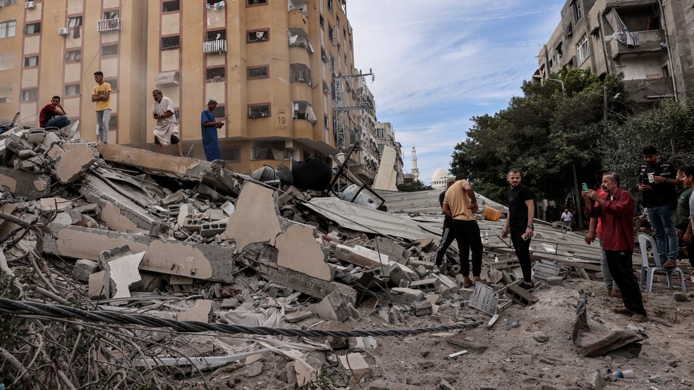 Pessoas observam destruição na Faixa de Gaza após bombardeios israelenses em reação a ataque do Hamas no dia 7 de outubro de 2023 — Foto: Mohammed Abed/AFP