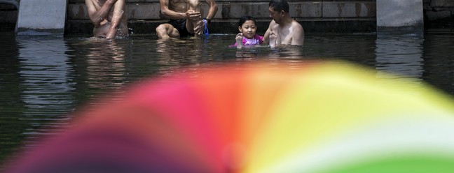 Moradores se refrescam em um canal urbano de Pequim, na segunda-feira, 3 de julho de 2023. Pequim relatou 9,8 dias consecutivos em que a temperatura ultrapassou 35 °C, informou o Centro Nacional do Clima do país na segunda. — Foto: AP Photo/Andy Wong