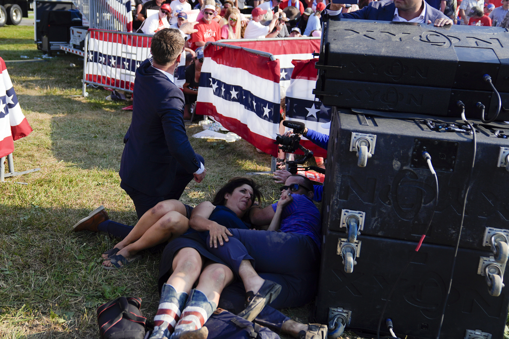 Público se protege de tiros em comício de Donald Trump — Foto: AP Foto/Evan Vucci