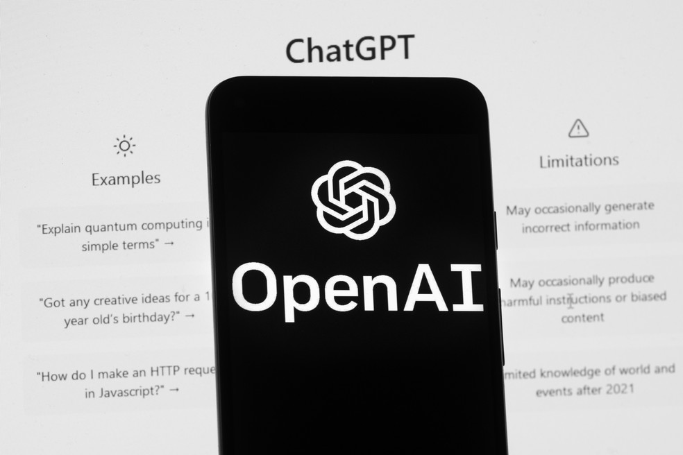 O logotipo da OpenAI é visto em um telefone celular em frente a uma tela de computador que exibe a tela inicial do ChatGPT — Foto: AP/Michael Dwyer, Arquivo