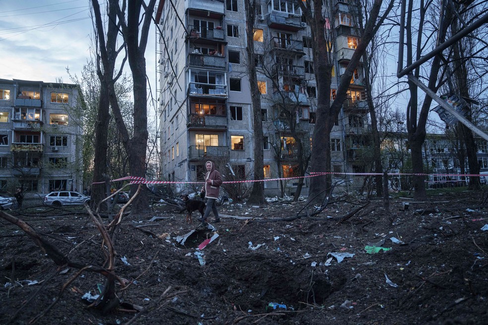 Mulher caminha entre escombros em área residencial de Kiev — Foto: AP/Evgeniy Maloletka