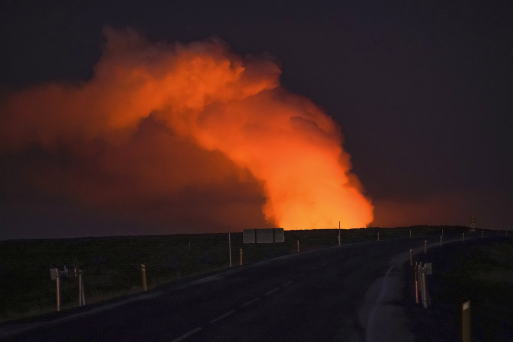 Uma coluna de fumaça é iluminada pela lava de um vulcão em erupção vista de Suðurstrandavegur, estrada que leva à cidade de Grindavík, no sudeste da Islândia. — Foto: AP Foto/ Marco Di Marco
