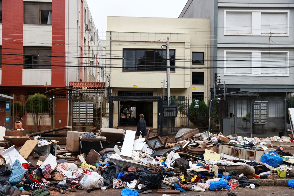 Pilhas de entulho e objetos atingidos pelas enchentes em Porto Alegre são deixados em rua da capital gaúcha, nesta segunda-feira (20), após a água baixar. — Foto: Diego Vara/Reuters