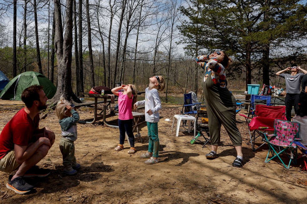Membros da família e amigos Debenham, que viajaram de Utah, Las Vegas e Illinois para vivenciar o eclipse solar total juntos, experimentam seus óculos de visualização do eclipse em seu acampamento um dia antes do evento em Camp Carew em Makanda, Illinois. — Foto: Evelyn Hockstein/Reuters