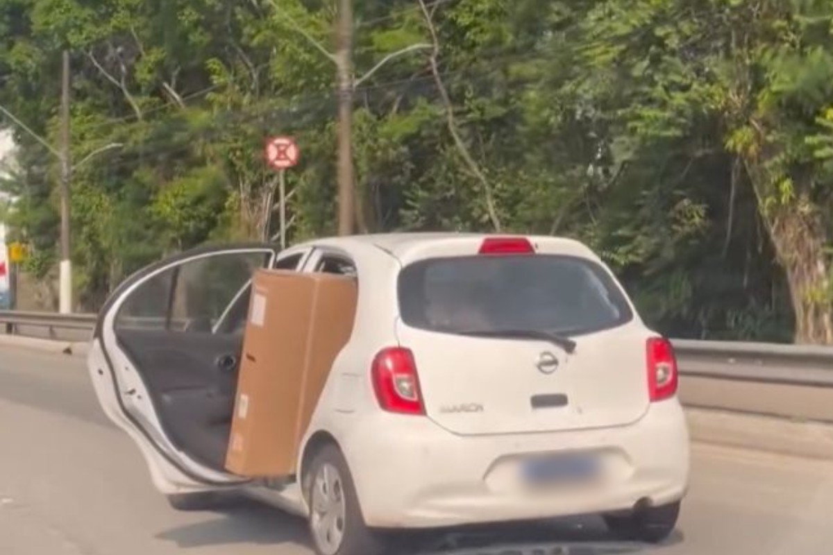 Motorista é flagrado dirigindo o carro com a porta traseira aberta para acomodar caixa e criança; VÍDEO