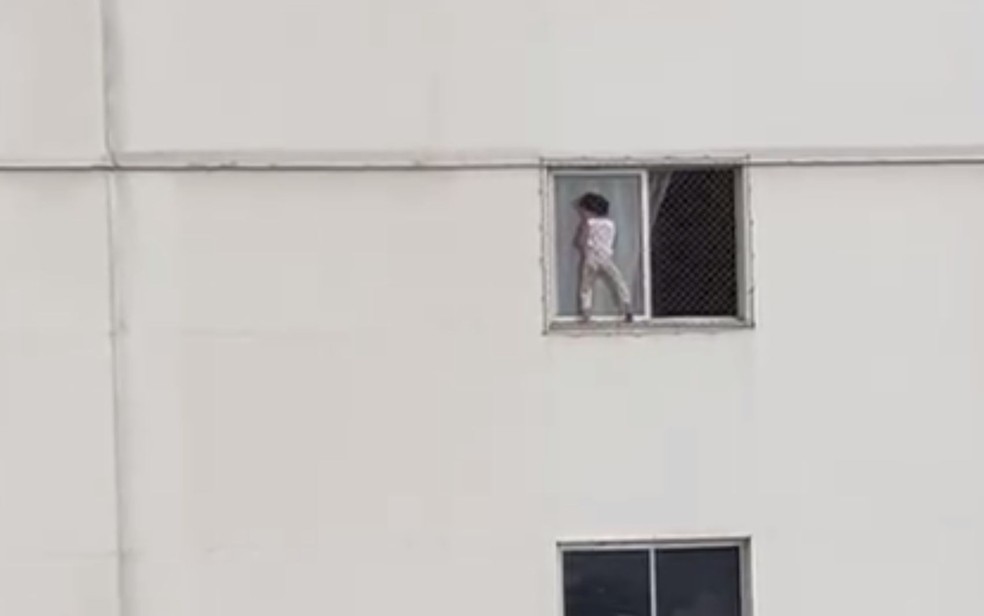 Criança brinca se apoiando em tela de proteção de janela em apartamento do 4º andar, em Goiânia — Foto: Reprodução/TV Anhanguera