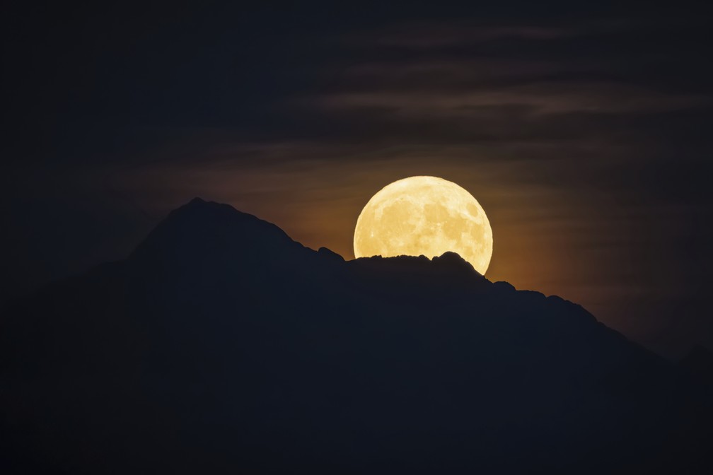 A superlua azul surge acima da montanha "Dent d'Oche", vista de Allaman, na Suíça. — Foto: AP