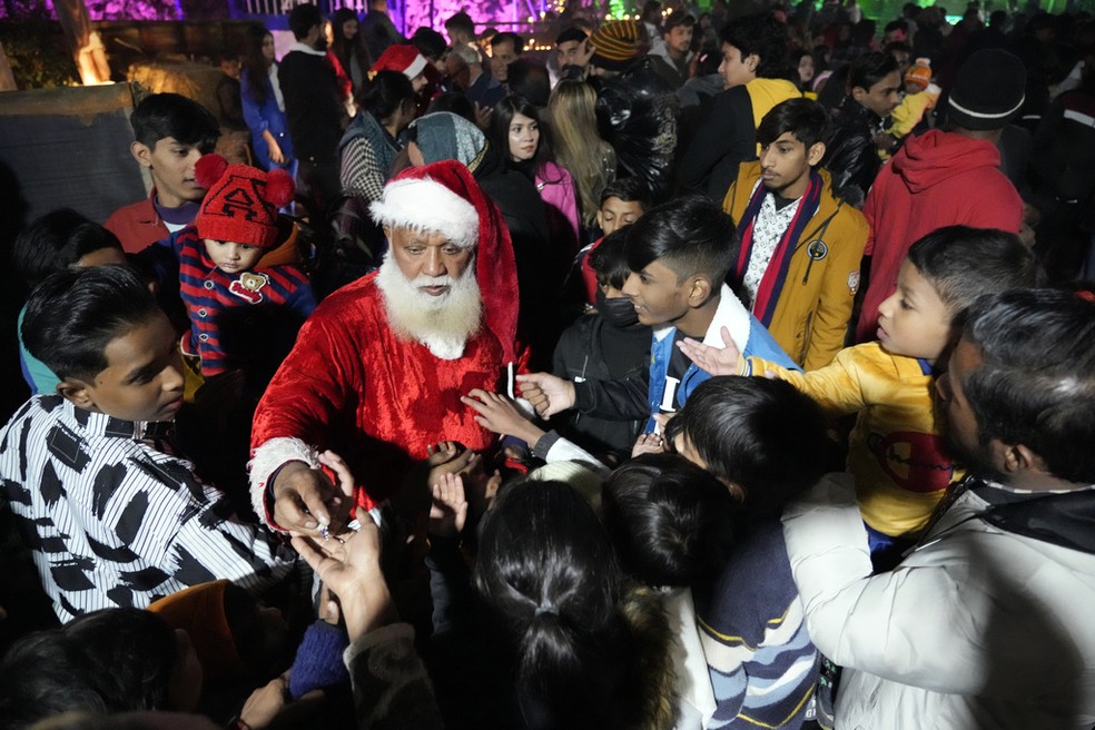 Um paquistanês cristão vestido de Papai Noel distribui presentes durante uma missa à meia-noite em Lahore, no Paquistão — Foto: K.M. Chaudary/AP