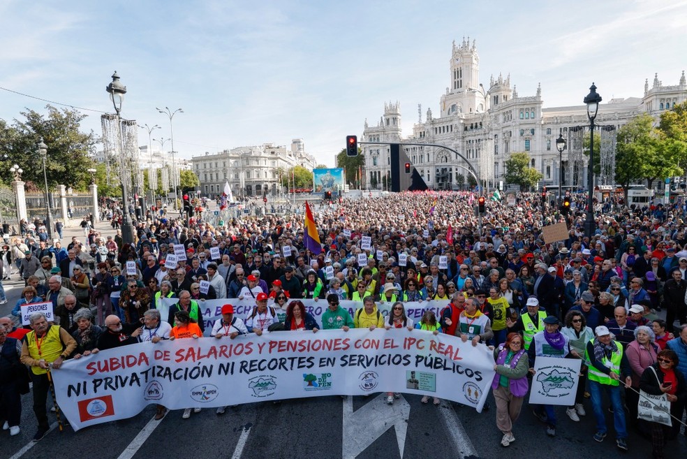 Manifestantes exibem faixas e bandeiras durante protesto em defesa das aposentadorias públicas e por melhores salários no centro de Madri, na Espanha, em 24 de outubro de 2026. — Foto: Oscar Del Pozo/AFP