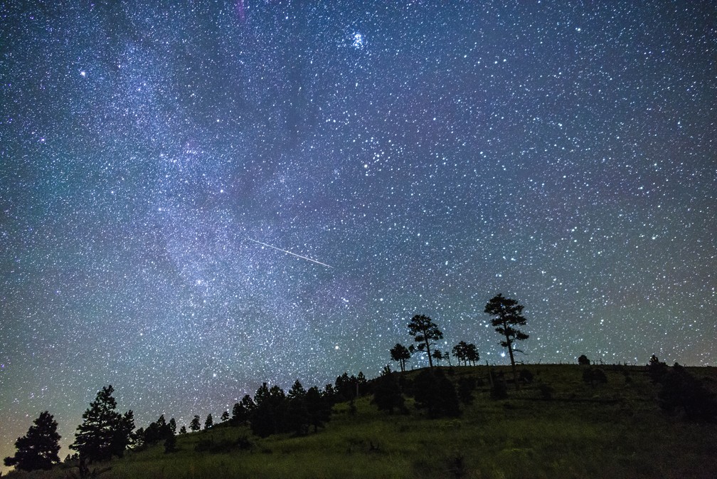 As chuvas de meteoros são fenômenos regulares. Na imagem, é possível ver o céu noturno perto das colinas próximas ao Pico O'Leary, no Arizona, Estados Unidos. Ao centro, um brilhante meteoro cruza o céu. — Foto: Domínio Público/Wikimedia