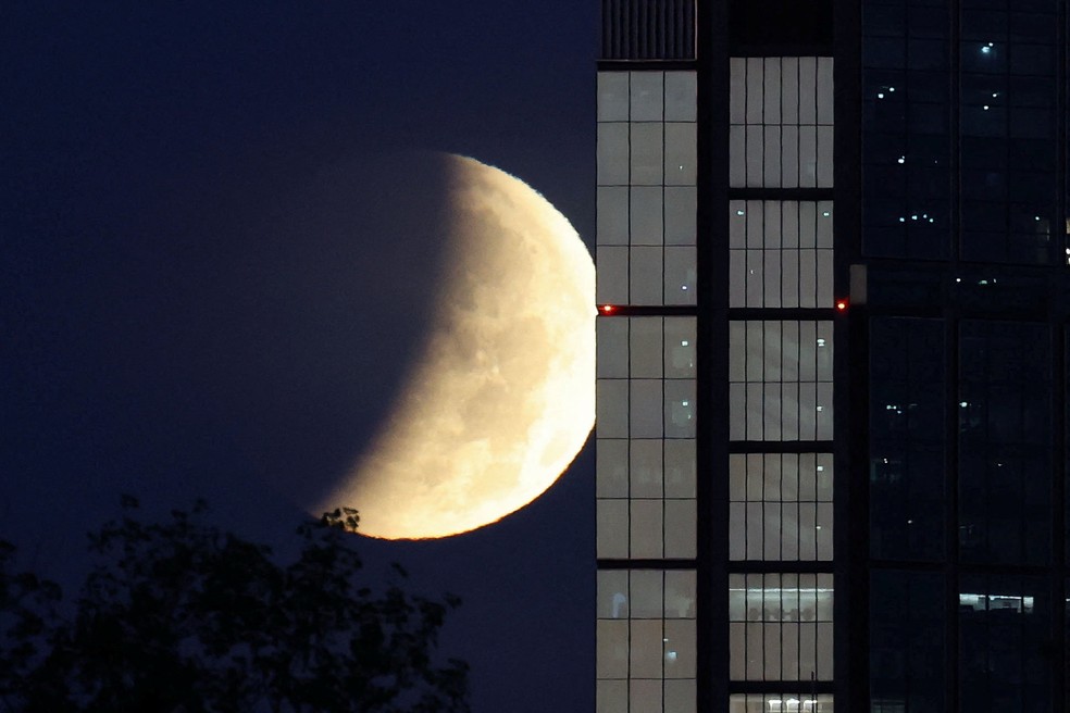 A lua durante um eclipse lunar parcial aparece no horizonte de Vars�via. � Foto: REUTERS/Kacper Pempel
