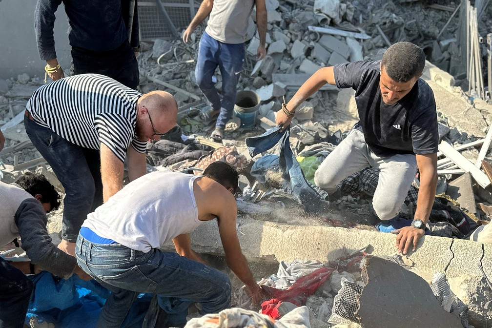 Pessoas trabalham para recuperar os corpos de palestinos no local dos ataques israelenses às casas, em meio ao conflito Israel-Hamas, em Beit Lahiya — Foto: REUTERS/Stringer