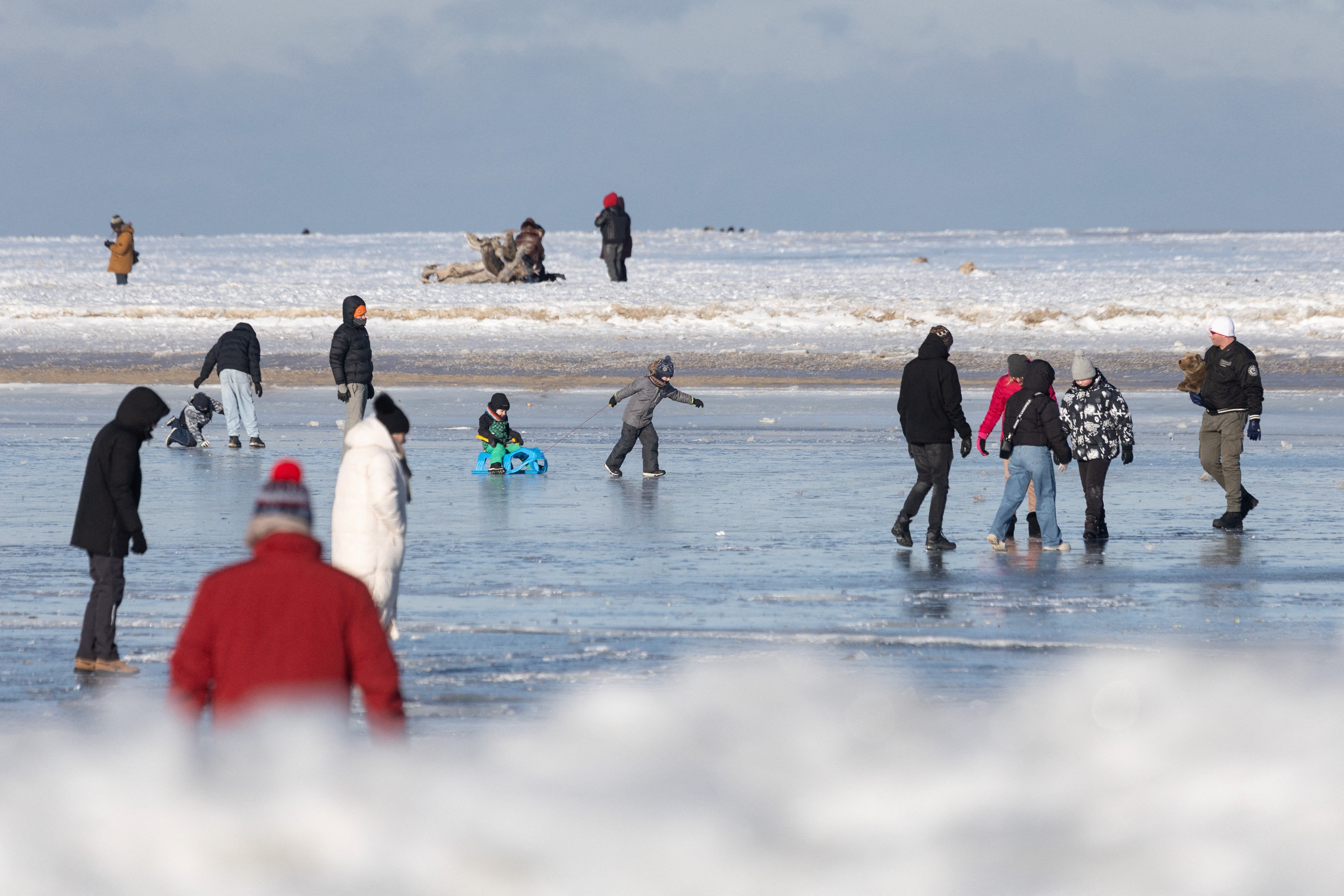 Moradores caminham e fazem patinação sobre o mar congelado em praia na Polônia; veja VÍDEO