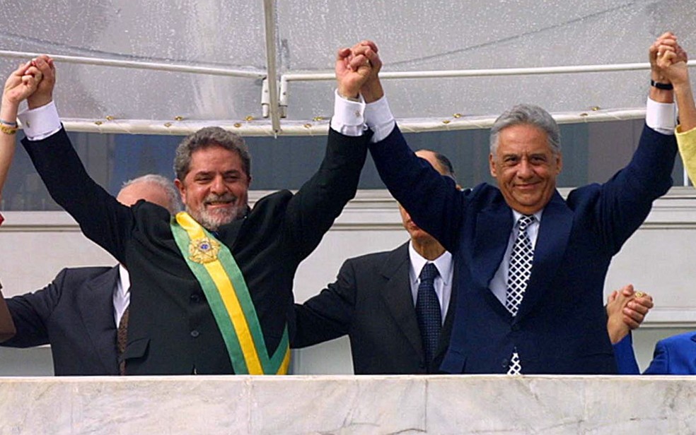 O ex-presidente Fernando Henrique Cardoso ergue os braços do presidente eleito e recém empossado Luiz Inácio Lula da Silva em cerimônia no Palácio do Planalto, em Brasília, em janeiro de 2003 — Foto: Ed Ferreira/Estadão Conteúdo/Arquivo