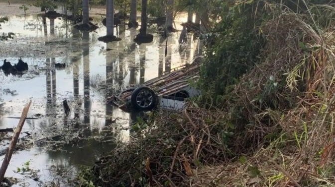 Motorista morre afogado e dois ficam feridos após carro capotar e cair em área alagada de rodovia em MT 