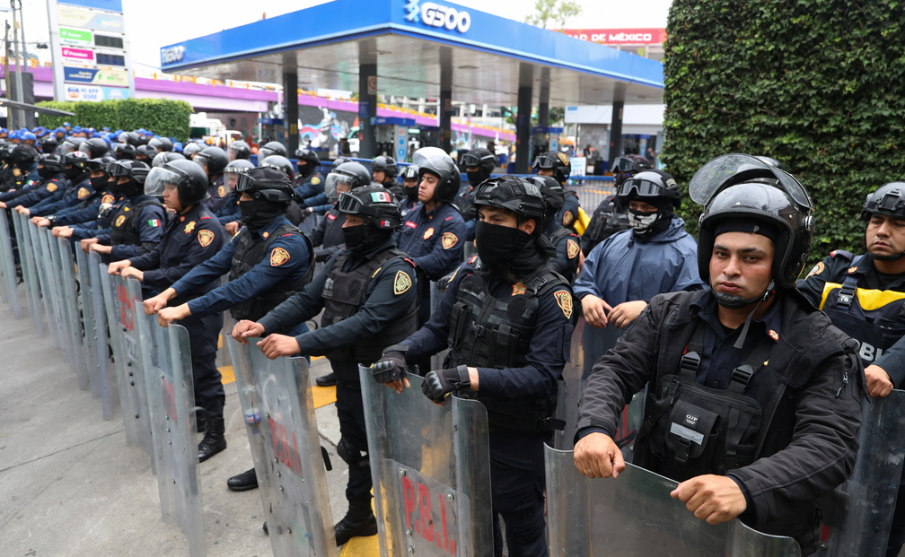 Policiais fazem barreira em uma calçada próxima ao Estádio Cidade do México, enquanto professores marcham em direção ao local em 9 de junho de 2026. — Foto: REUTERS/Luis Cortes.