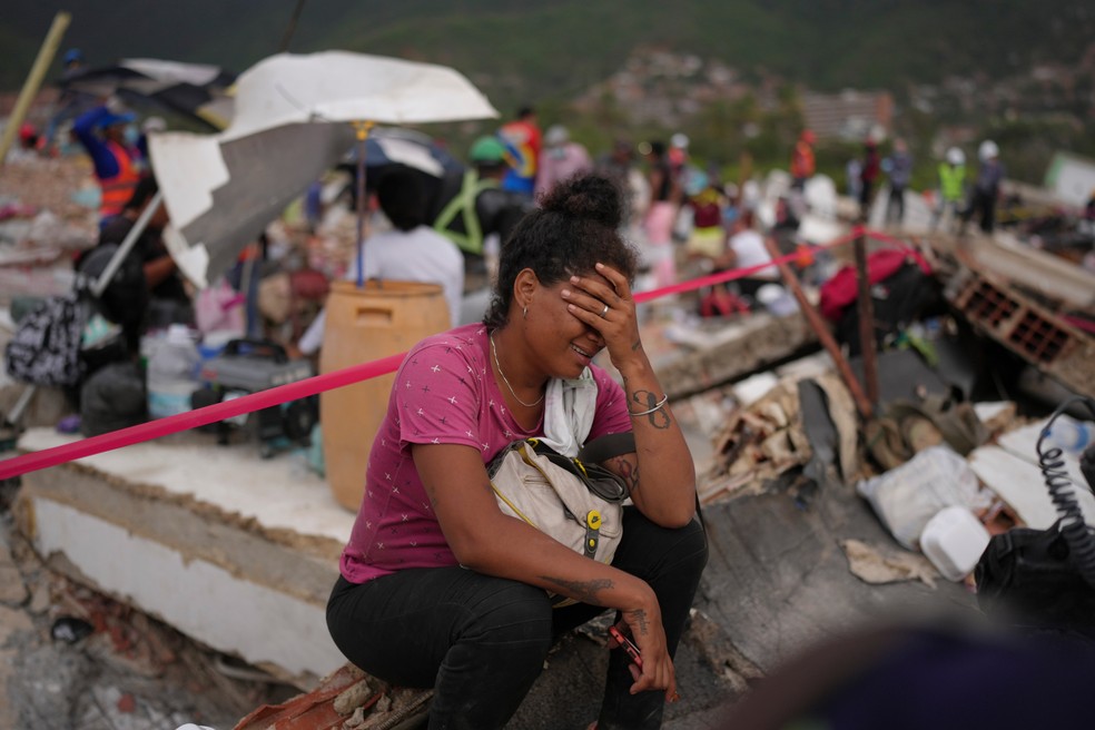 Khaterine Roa chora enquanto membros do Corpo de Bombeiros do Condado de Los Angeles buscam sobreviventes em um prédio que desabou durante os terremotos que atingiram La Guaira, na Venezuela. — Foto: Matias Delacroix/AP Photo