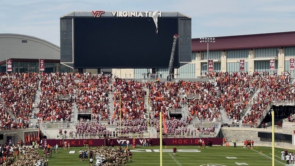 Funcionários em um elevador trabalham para resgatar um paraquedista que caiu no placar do Lane Stadium antes do jogo de futebol americano universitário da Virginia Tech — Foto: Ben Walls/WRIC8 via AP