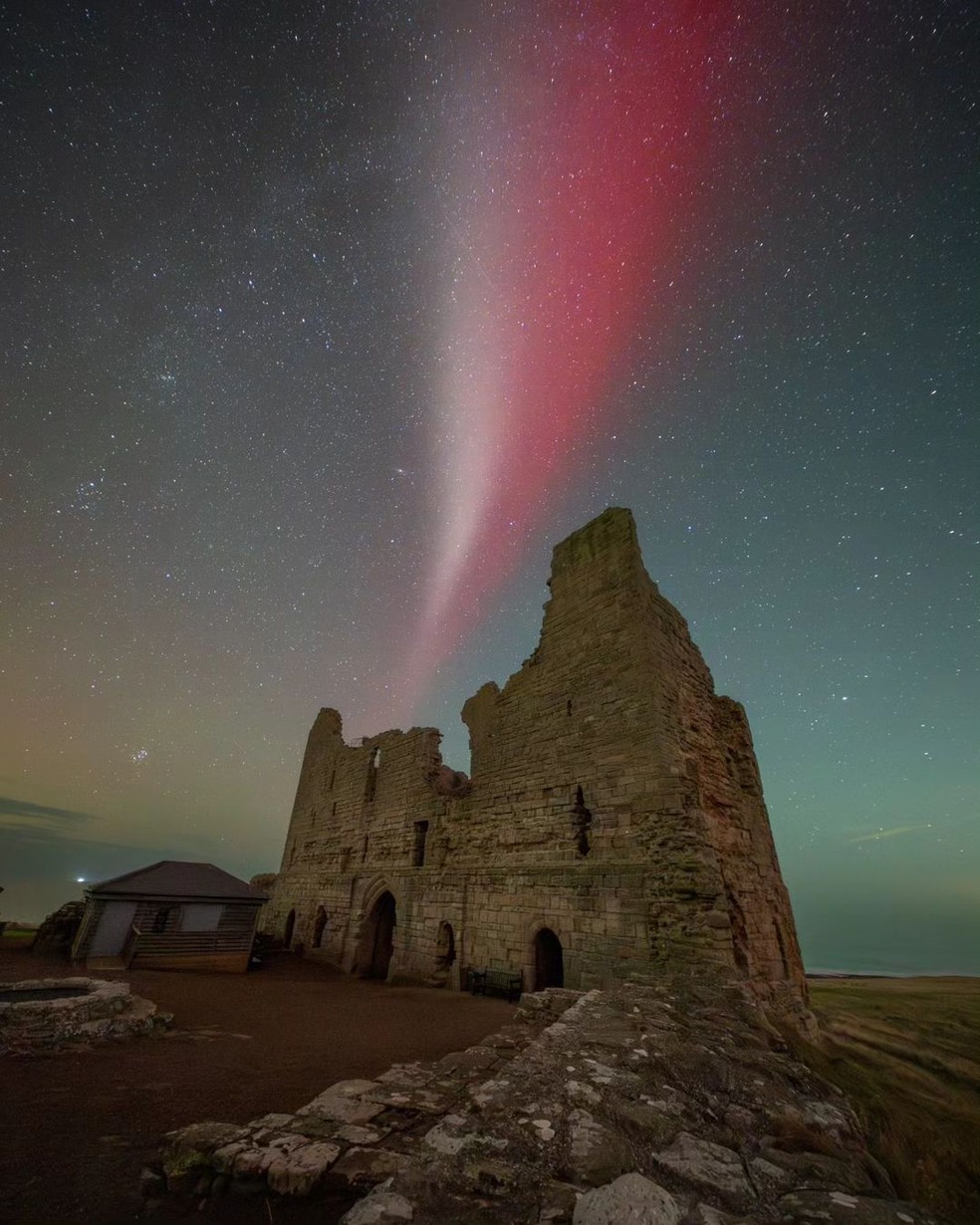 O fenômeno Steve visto no céu sobre o Castelo de Dunstanburgh, o maior castelo da Northumberland, no norte da Inglaterra, na segunda-feira, 7 de outubro de 2024. — Foto: Ian Sproat