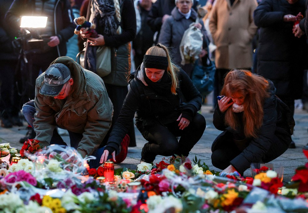 Pessoas deixam flores próximo a feira natalina onde um carro atropelou a multidão e deixou mortos, na Alemanha — Foto: Christian Mang/Reuters