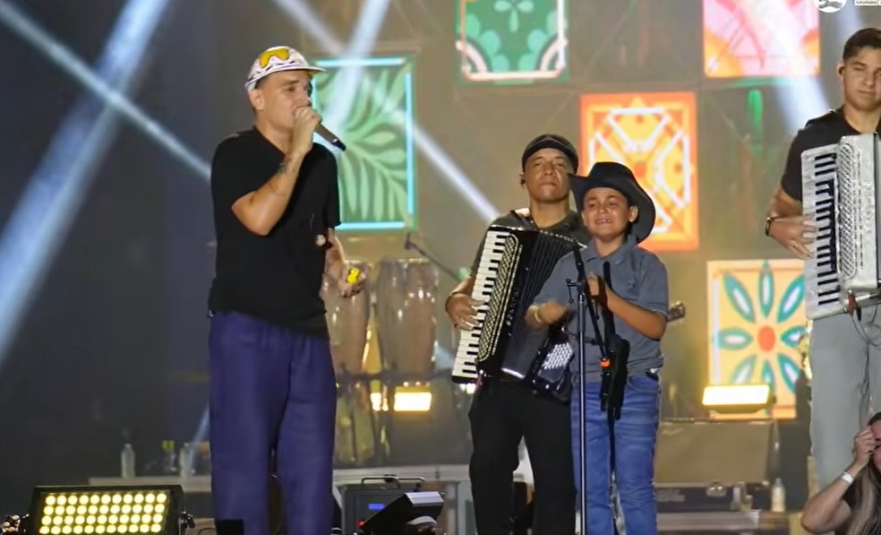 Menino de 9 anos se emociona ao tocar triângulo com João Gomes em show no interior da Paraíba — Foto: Reprodução/São João de Santa Luzia