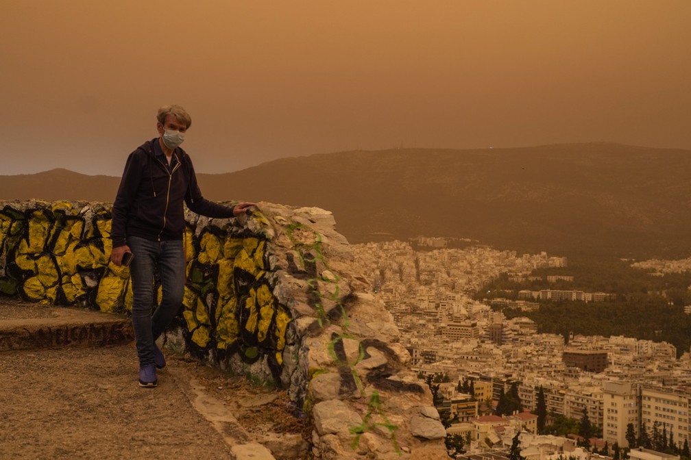 Turista utiliza máscara durante passeio para observar Atenas, na Grécia, por conta da nuvem de areia, em 23 de abril de 2024. — Foto: Petros Giannakouris/ AP