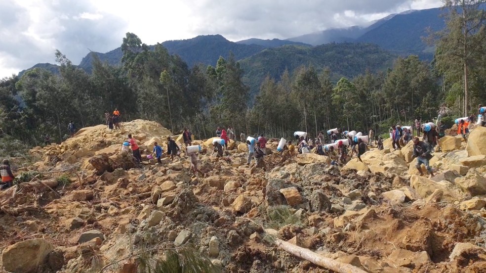 Moradores do vilarejo de Kaokalam, na região central de Papua Nova Guiné, caminhão sobre pedras após deslizamento de terra que matou mais de 100, em 24 de maio de 2024. — Foto: Andrew Ruing via Reuters