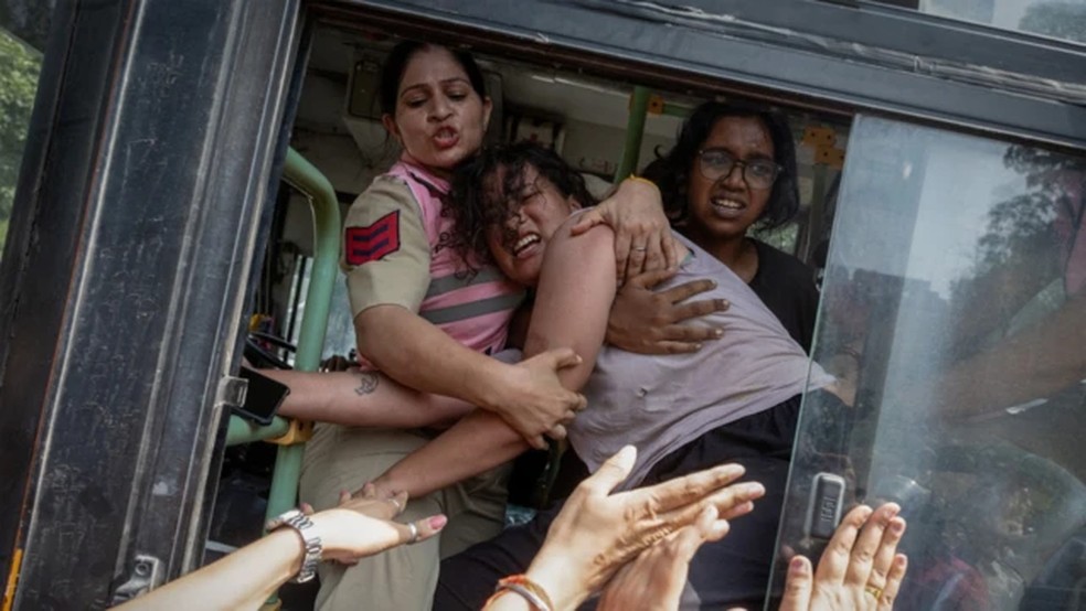 Manifestantes se posicionaram diante das viaturas policiais para impedir que levassem os detidos — Foto: Reuters via BBC