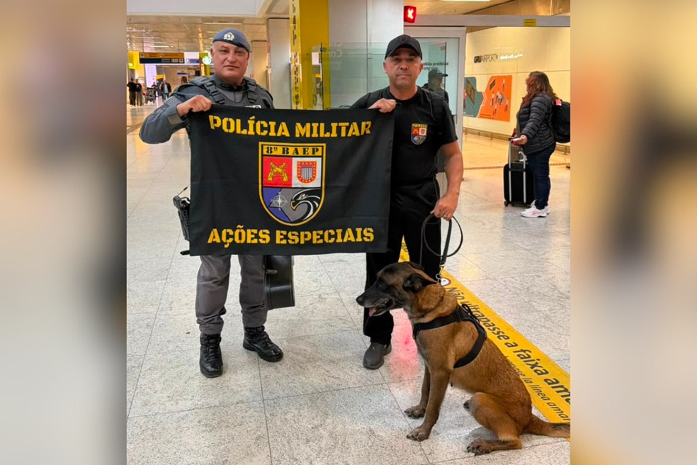 Subtenente Júnior - comandante do Canil, cabo Vesco e Kira no aeroporto, de volta ao Brasil — Foto: 8º Baep